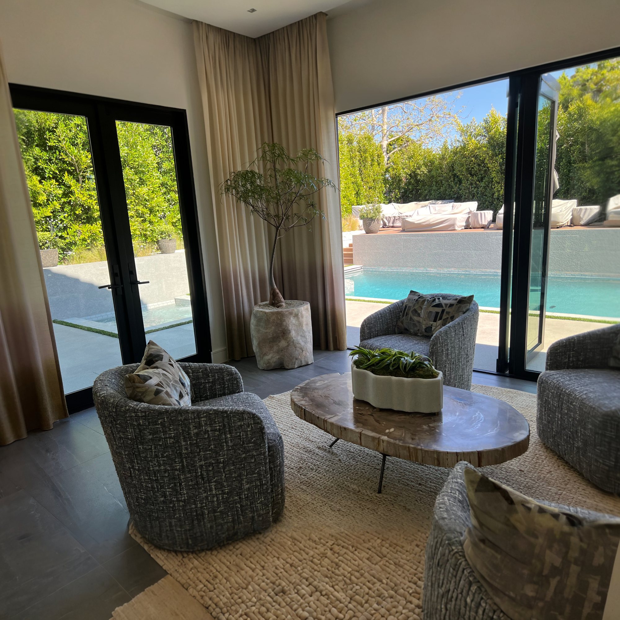 Round sitting room with grey swivel chairs and pool view